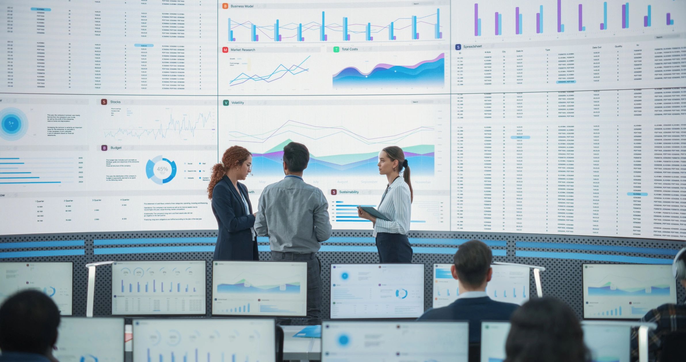 Project team collaborating in front of data screens